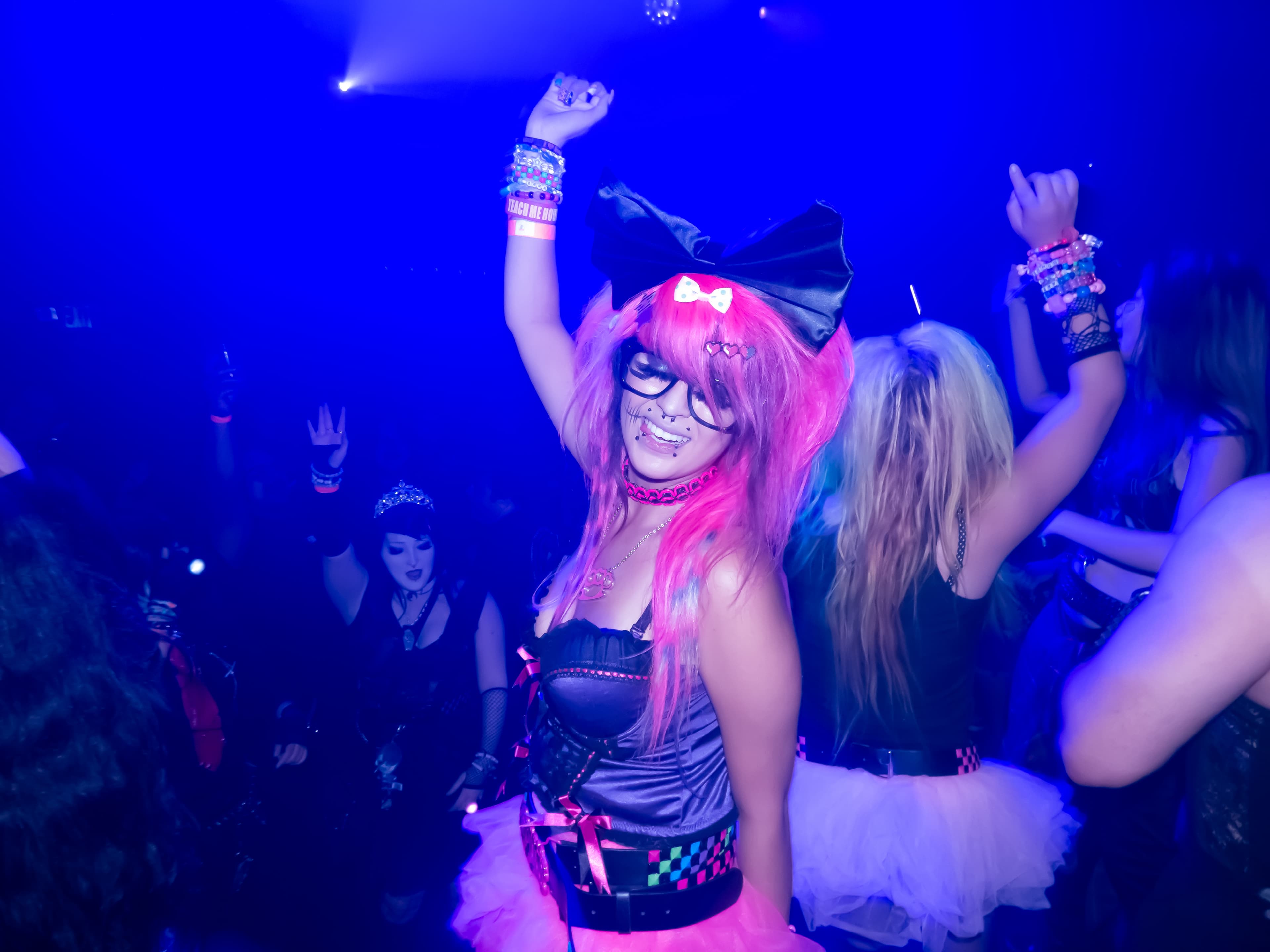 Event photography by Chase Tipton - woman dancing energetically in a club, colorful lights and crowd in the background