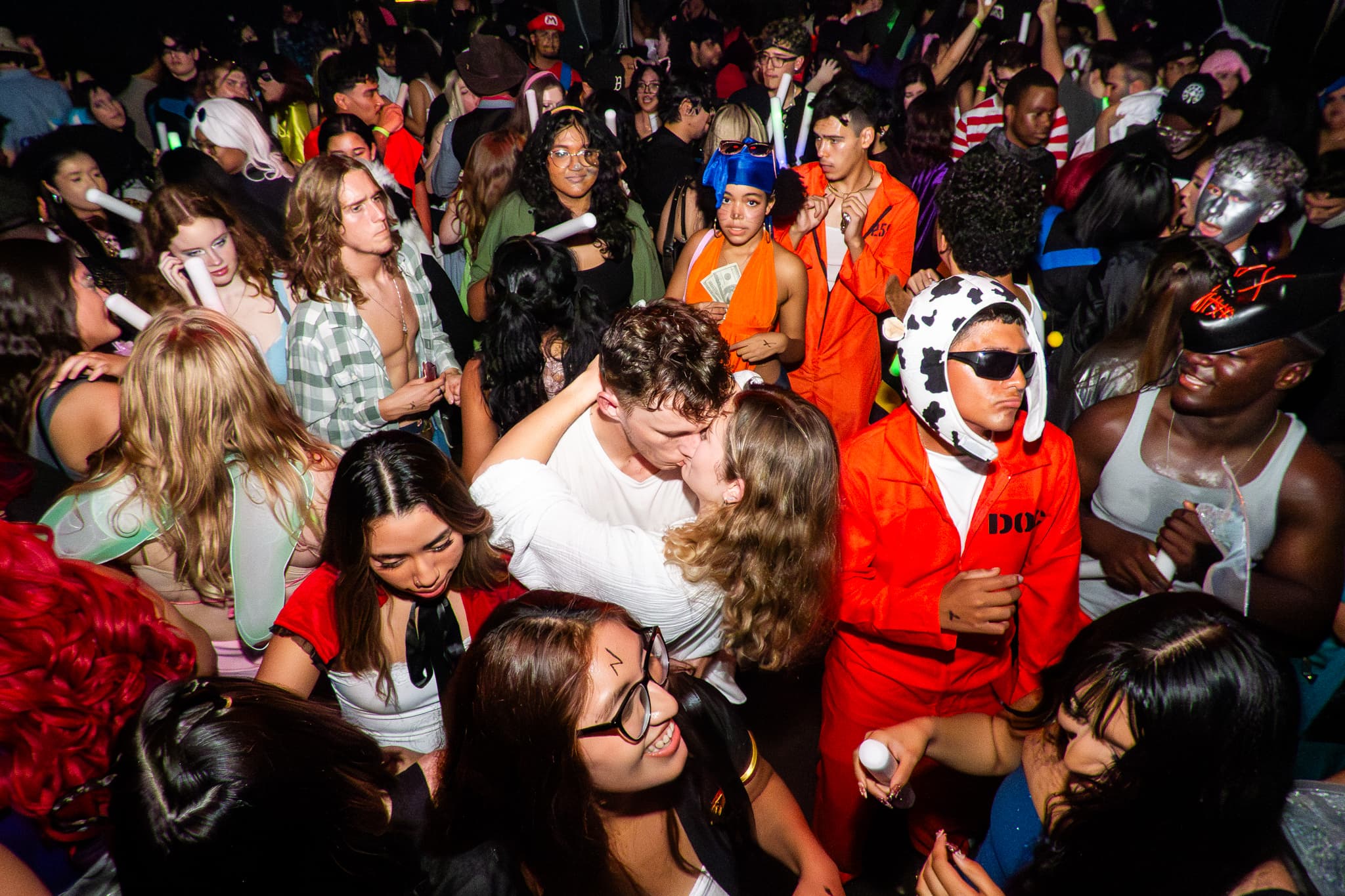Event photography by Chase Tipton - Candid moment at club, people dancing in costumes and enjoying the music, couple kissing in the center